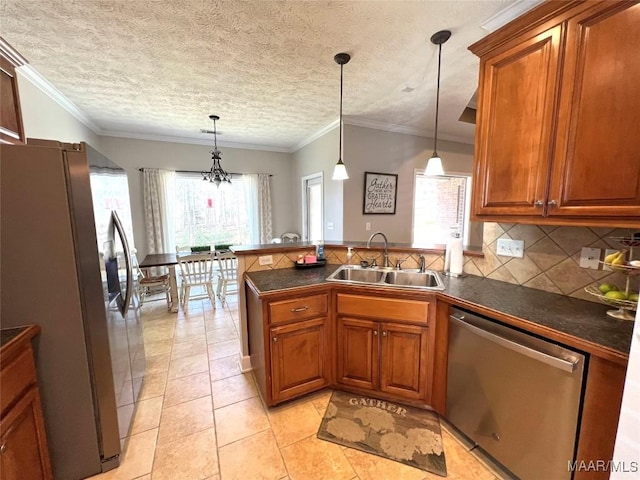 kitchen featuring a peninsula, a sink, appliances with stainless steel finishes, a wealth of natural light, and dark countertops