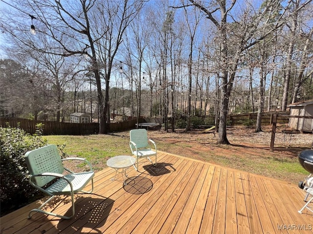 deck featuring a lawn, an outdoor structure, and fence