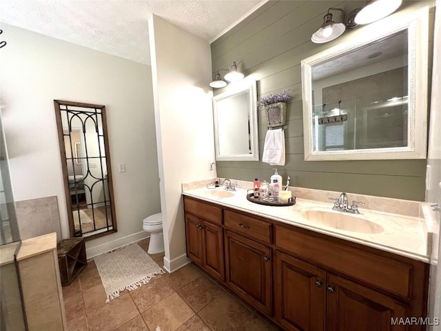 bathroom featuring a sink, a textured ceiling, toilet, and double vanity