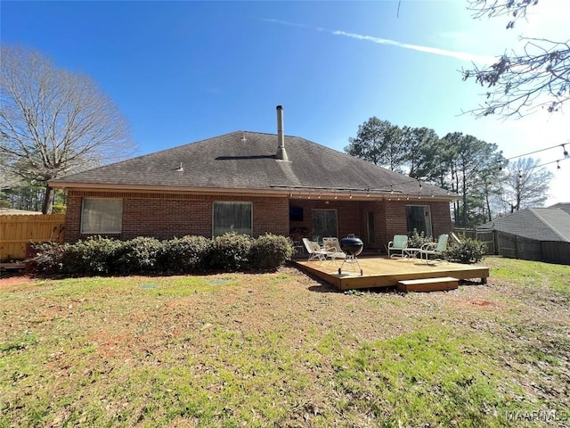 back of house with a yard, brick siding, fence, and a deck