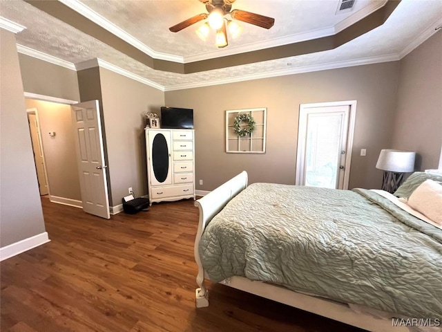 bedroom featuring crown molding, a raised ceiling, visible vents, wood finished floors, and baseboards