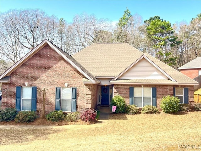 ranch-style home with brick siding, a shingled roof, and a front yard