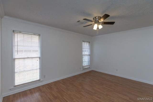 unfurnished room with ornamental molding, wood finished floors, visible vents, and a healthy amount of sunlight