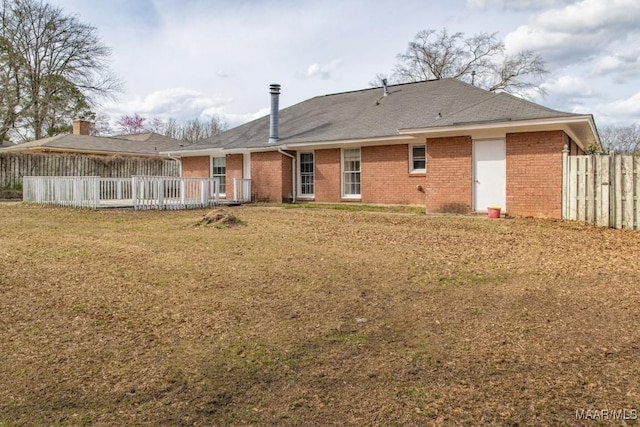 back of house featuring fence, a lawn, and brick siding