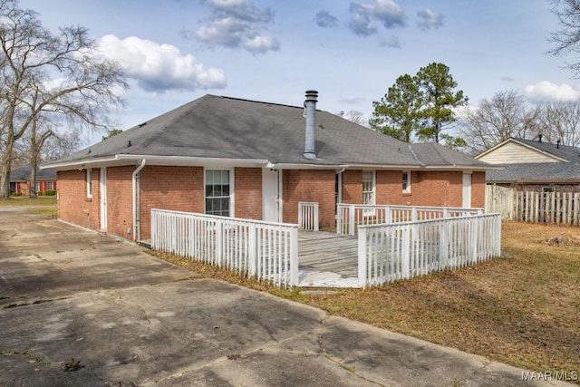 rear view of property featuring brick siding and fence