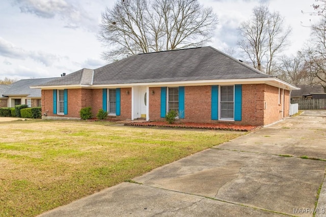 ranch-style house featuring a shingled roof, brick siding, fence, and a front lawn