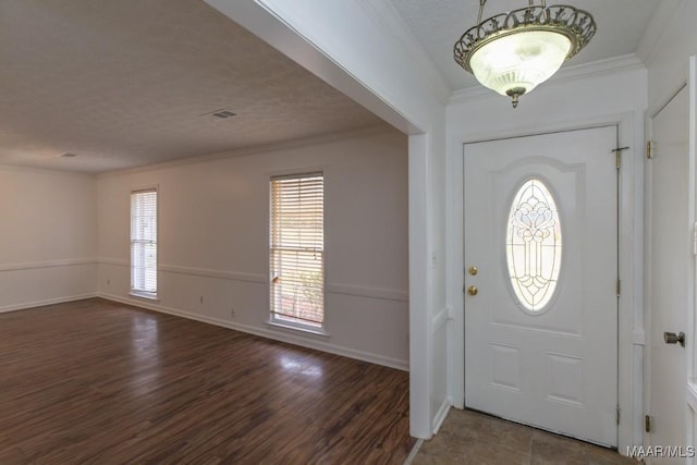 entryway with a textured ceiling, baseboards, dark wood-type flooring, and crown molding