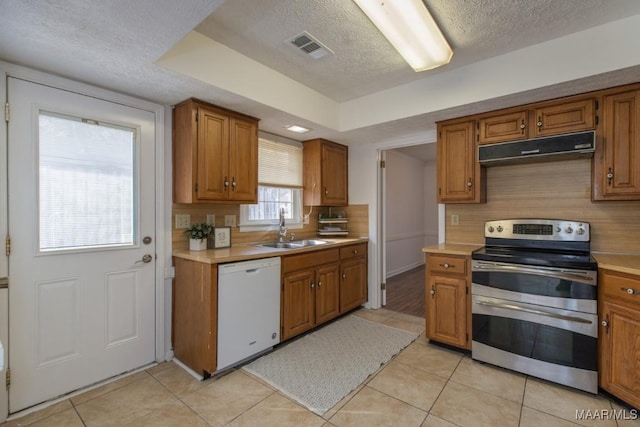 kitchen with dishwasher, light countertops, under cabinet range hood, double oven range, and a sink