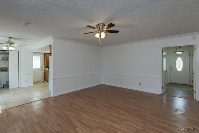 unfurnished living room with a textured ceiling, ceiling fan, visible vents, light wood-style floors, and ornamental molding