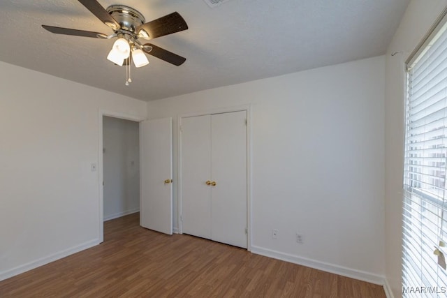 unfurnished bedroom featuring multiple windows, wood finished floors, and baseboards