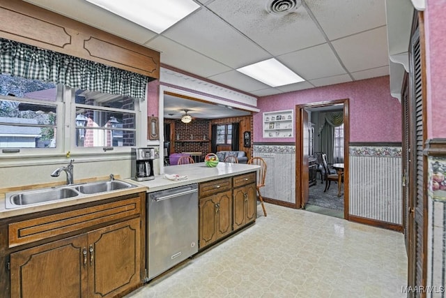 kitchen with dishwasher, light floors, a sink, and a paneled ceiling