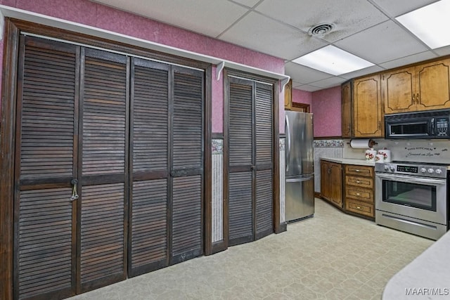kitchen featuring a drop ceiling, stainless steel appliances, visible vents, light countertops, and brown cabinets