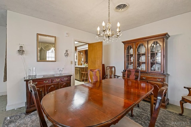 dining room featuring dark carpet, visible vents, a notable chandelier, and baseboards