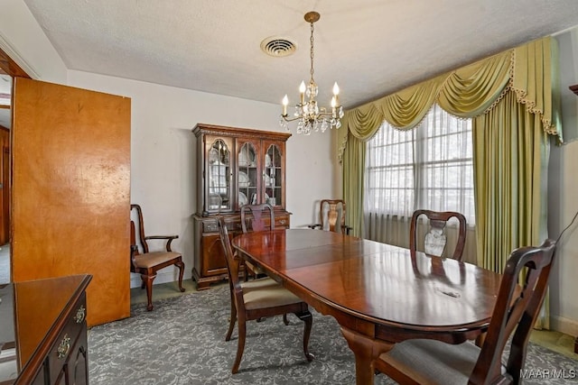 carpeted dining space with a textured ceiling, visible vents, and an inviting chandelier