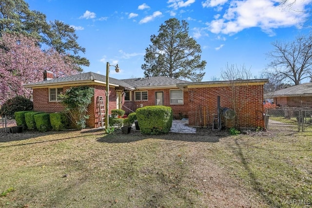 ranch-style house with a gate, brick siding, fence, and a front lawn