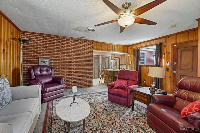 living room with carpet floors, visible vents, wood walls, and brick wall