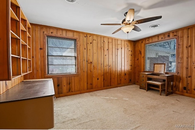 unfurnished office featuring carpet floors, visible vents, plenty of natural light, and a ceiling fan