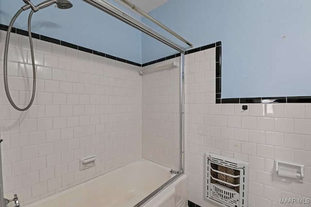 full bath featuring bath / shower combo with glass door, tile walls, and heating unit