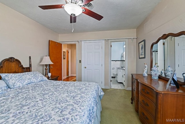 bedroom featuring a textured ceiling, ensuite bathroom, light carpet, a ceiling fan, and baseboards