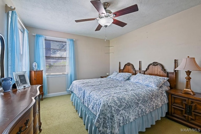 bedroom featuring light carpet, baseboards, a ceiling fan, and a textured ceiling