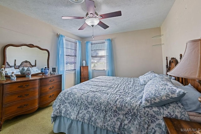 bedroom featuring light carpet, ceiling fan, and a textured ceiling