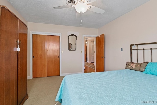 bedroom featuring a ceiling fan, light carpet, a textured ceiling, and baseboards