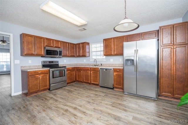 kitchen with light countertops, appliances with stainless steel finishes, light wood-style flooring, and brown cabinets