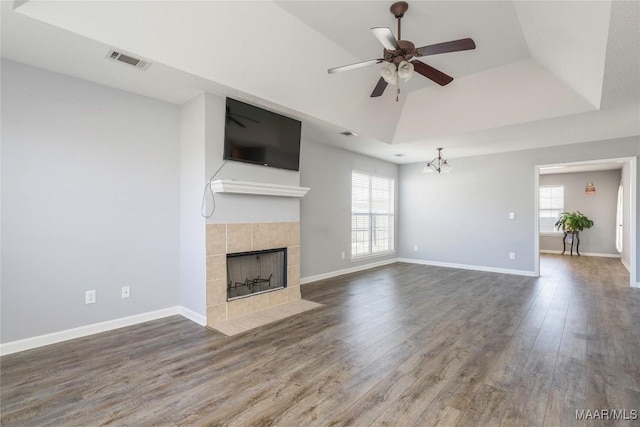 unfurnished living room with a raised ceiling, a tile fireplace, wood finished floors, and visible vents