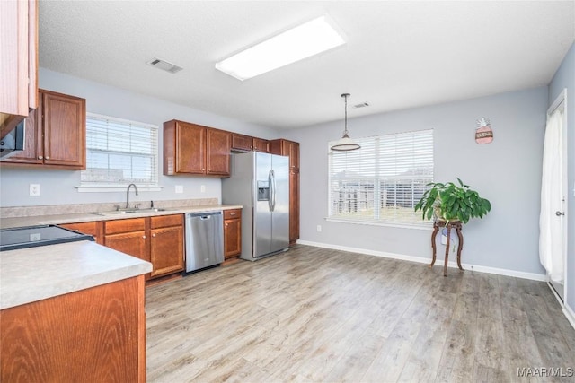 kitchen with light wood finished floors, visible vents, stainless steel appliances, light countertops, and a sink