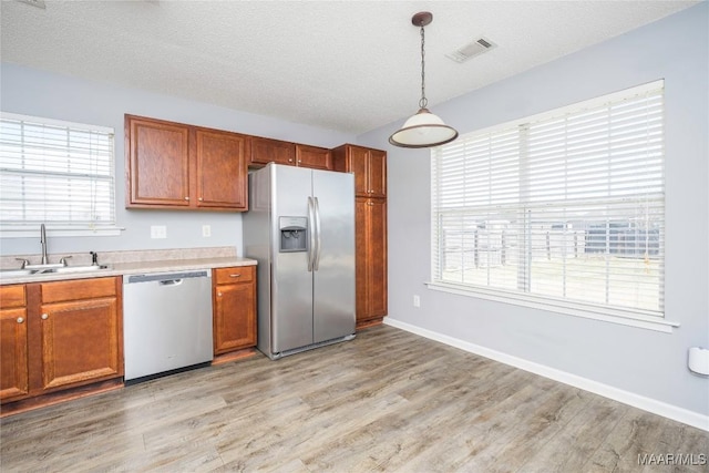 kitchen with visible vents, appliances with stainless steel finishes, light countertops, a textured ceiling, and a sink