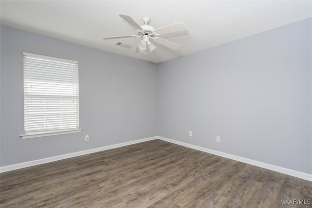 empty room with visible vents, wood finished floors, a ceiling fan, and baseboards