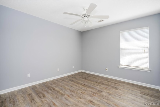 unfurnished room with baseboards, visible vents, ceiling fan, and wood finished floors