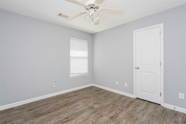 empty room with a ceiling fan, visible vents, baseboards, and wood finished floors