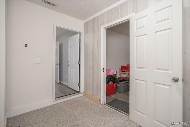 hall with carpet floors, visible vents, a textured ceiling, and baseboards