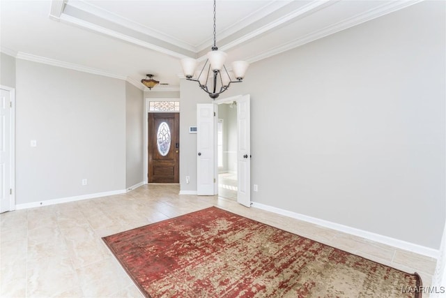 entrance foyer with ornamental molding, a tray ceiling, a chandelier, and baseboards