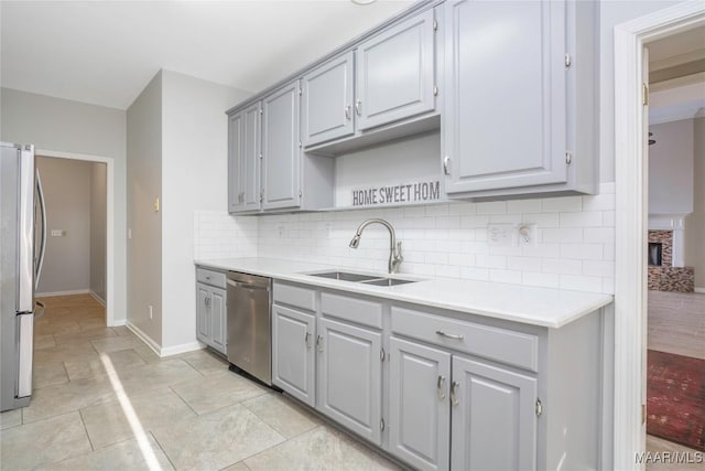 kitchen featuring stainless steel appliances, gray cabinets, a sink, and tasteful backsplash