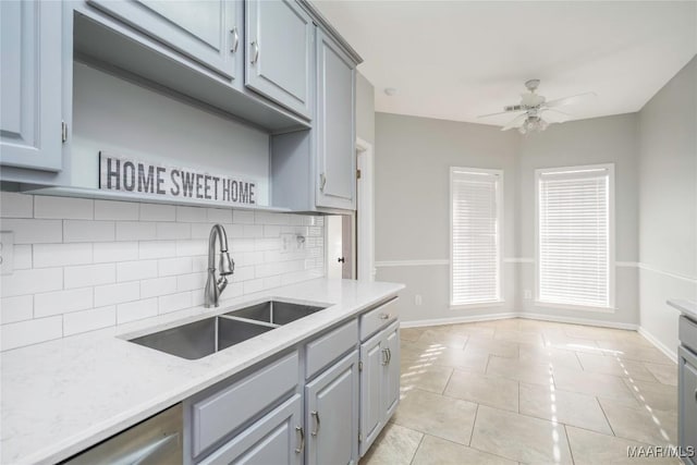 kitchen featuring light tile patterned floors, tasteful backsplash, gray cabinetry, a ceiling fan, and a sink