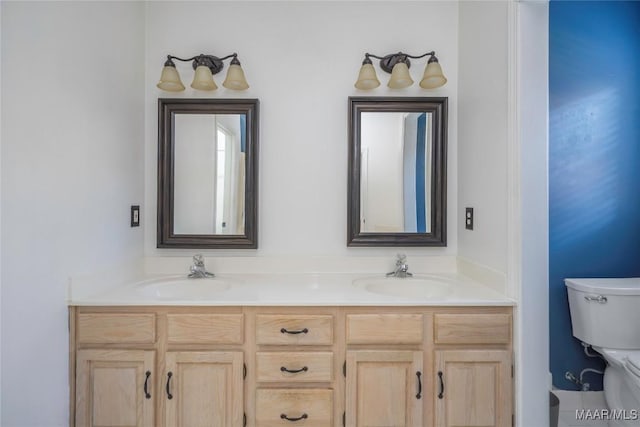 full bathroom with toilet, double vanity, and a sink