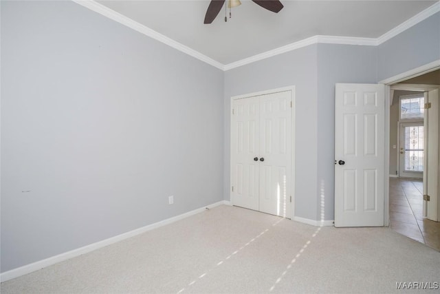 unfurnished bedroom with baseboards, ornamental molding, a closet, and light colored carpet