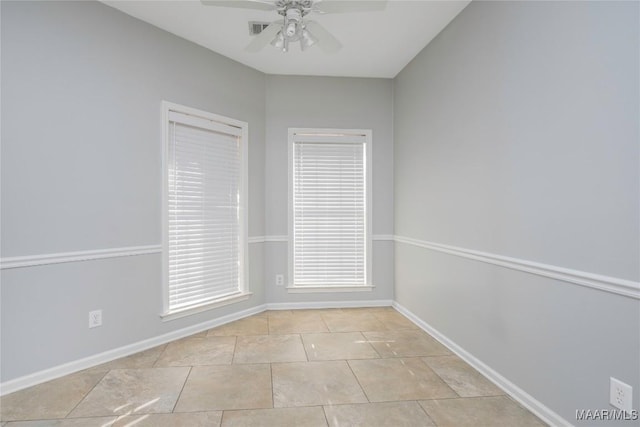 empty room with ceiling fan, light tile patterned floors, visible vents, and baseboards