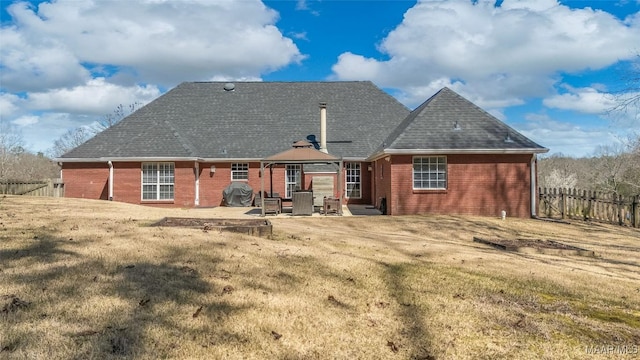 rear view of property featuring a patio, brick siding, fence, a gazebo, and a lawn