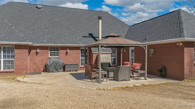 rear view of house featuring brick siding, roof with shingles, a patio, and a gazebo