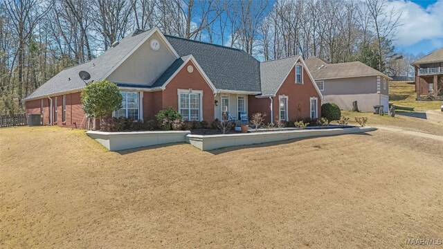 view of front of house with brick siding, a front lawn, and central air condition unit