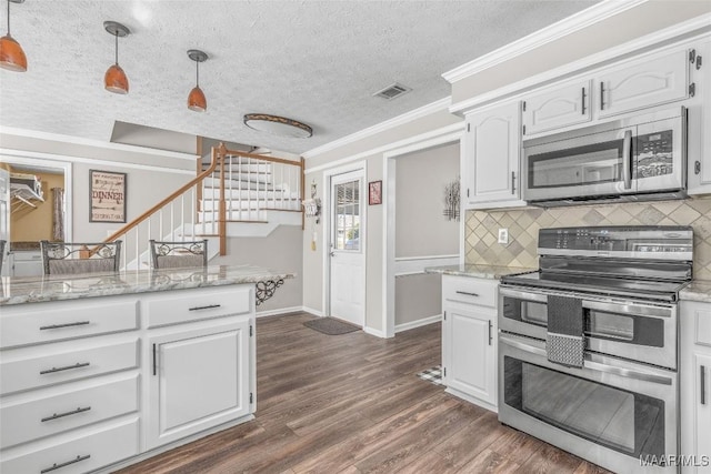 kitchen featuring crown molding, stainless steel appliances, hanging light fixtures, dark wood-type flooring, and white cabinetry