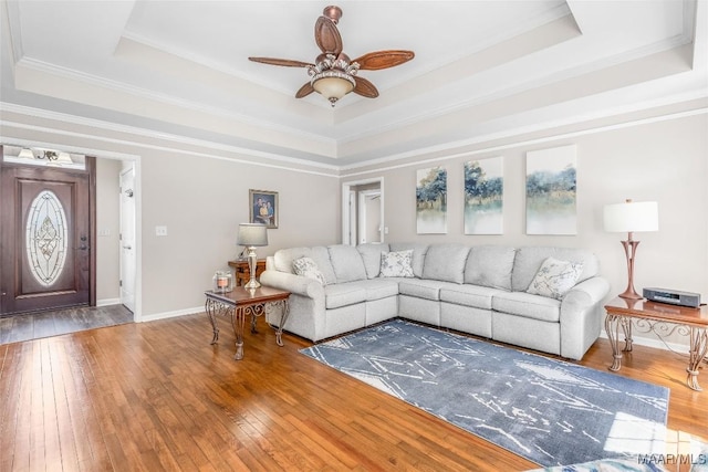 living area featuring hardwood / wood-style floors, a raised ceiling, and baseboards