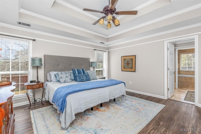 bedroom featuring a raised ceiling, visible vents, baseboards, and wood finished floors