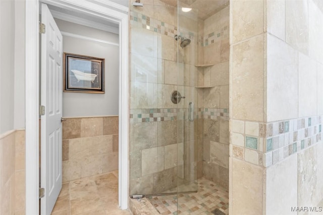 full bathroom featuring a stall shower, wainscoting, and tile walls