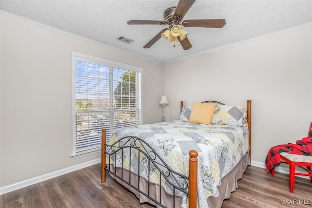 bedroom featuring baseboards, visible vents, wood finished floors, crown molding, and a textured ceiling