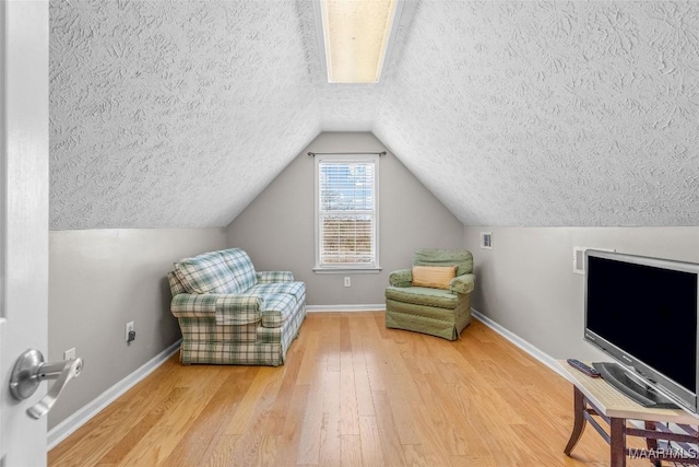 living area featuring lofted ceiling, baseboards, a textured ceiling, and hardwood / wood-style floors