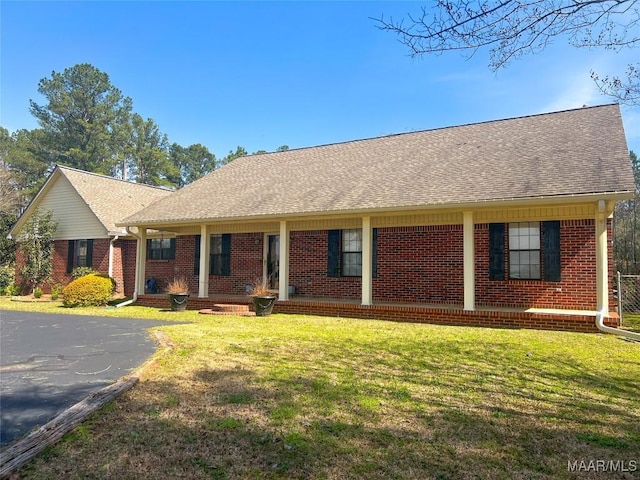 ranch-style home with brick siding, a front yard, and a shingled roof